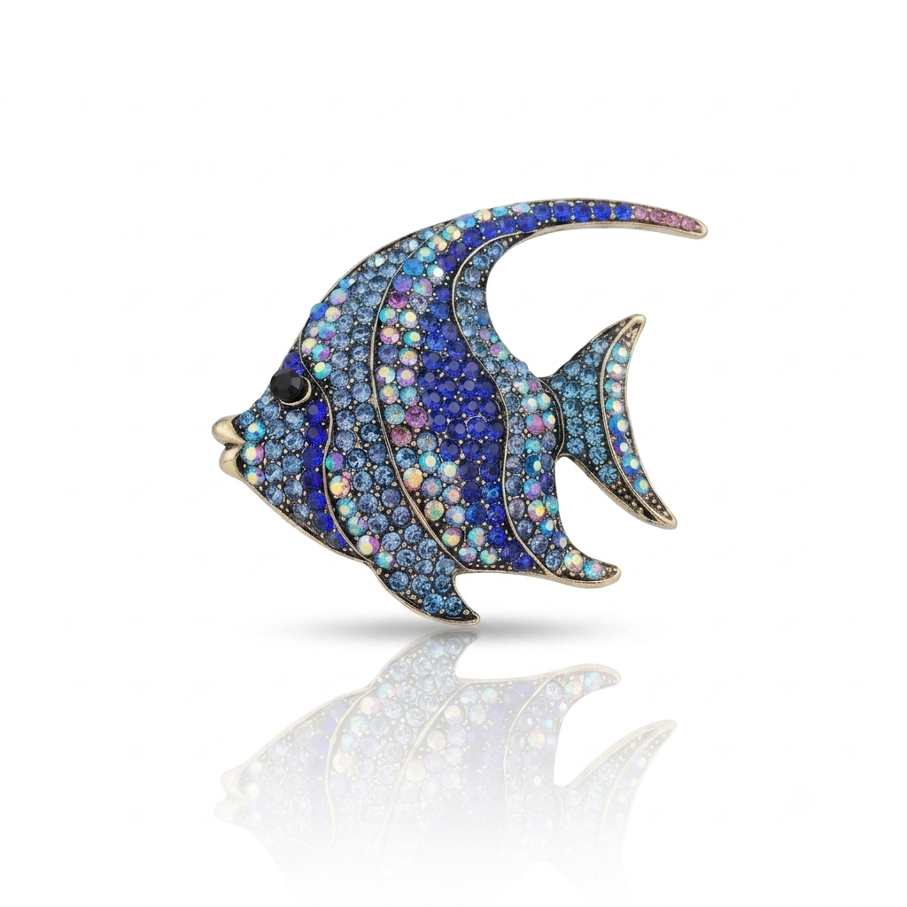A fish-shaped brooch or pin paved with iridescent blue, purple, and pink rhinestones, featuring a gold-tone outline and a small black eye, shown on a white background with a soft reflection below.