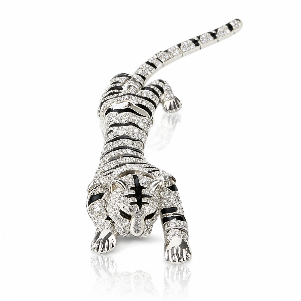 A white gold or platinum tiger-shaped brooch paved with clear stones and accented with black enamel stripes, shown on a reflective white background.