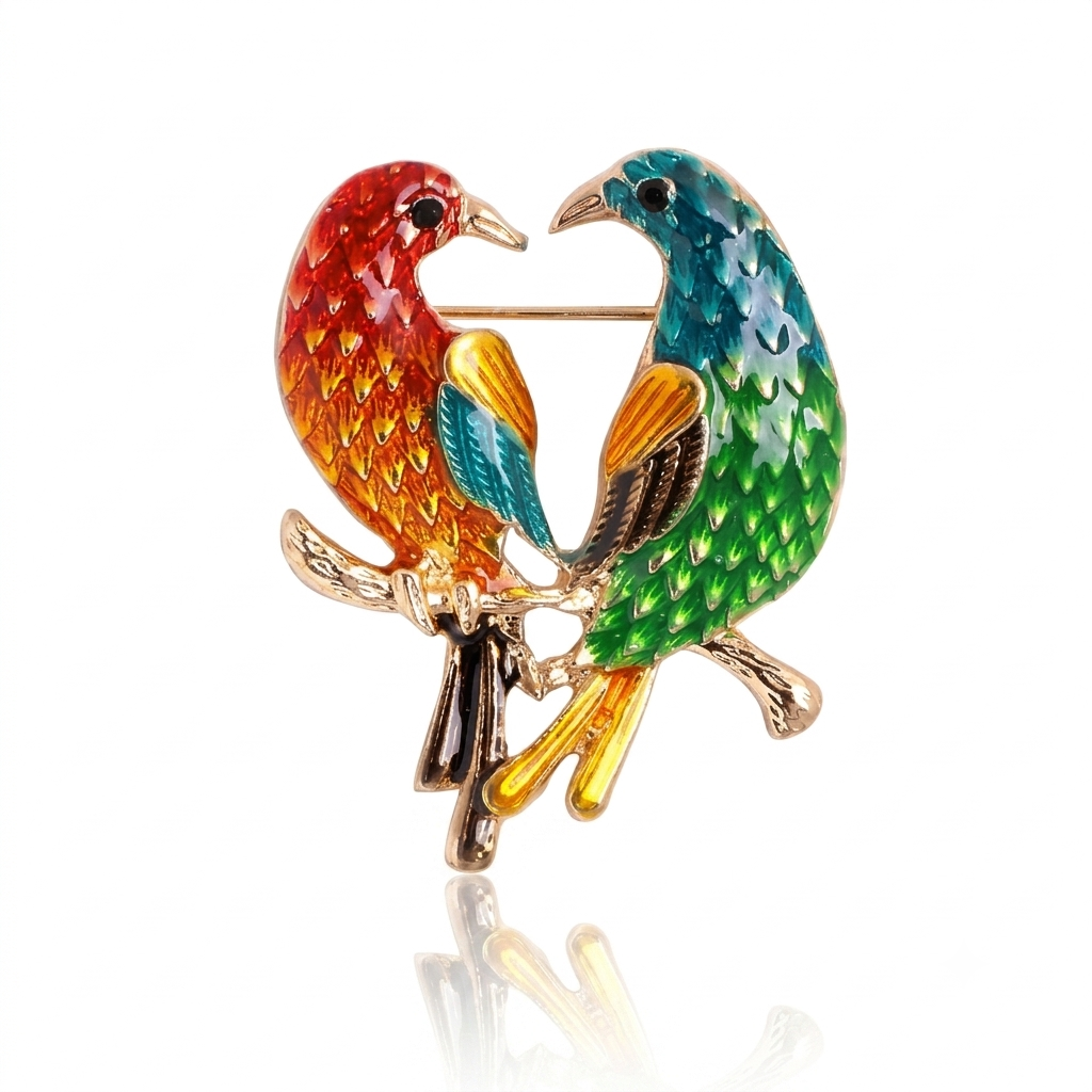 A colorful enamel bird brooch featuring two perched birds with red, orange, blue, green, yellow, and brown enamel details on a gold-tone metal base, shown on a white background with a faint reflection below.