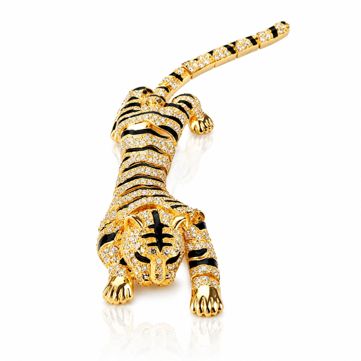 A gold tiger-shaped brooch or pin, covered in small clear pavé stones and accented with black enamel stripes, shown on a clean white background with a soft reflection.